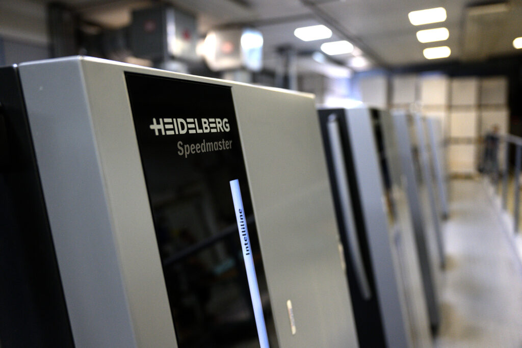 2025_Warlich_Druck_Meckenheim_August_JR_00630 Nahaufnahme der Druckmaschine, sodass Heidelberger Speedmaster zu lesen ist.