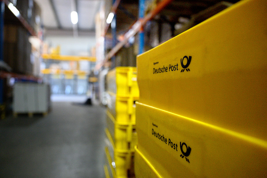 2025_Warlich_Druck_Meckenheim_August_JR_01217 Zwei übereinandergestapelte Postkisten in einer Halle.