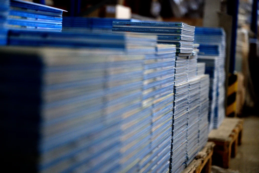 Aufeinander gestapelte eingeschweißte Bücher in einer Lagerhalle.